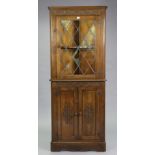 A reproduction carved oak tall standing corner cabinet the upper part fitted with a shaped shelf