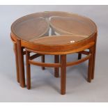 A teak nest of four occasional tables (three under one) the larger table having a plate glass top, &
