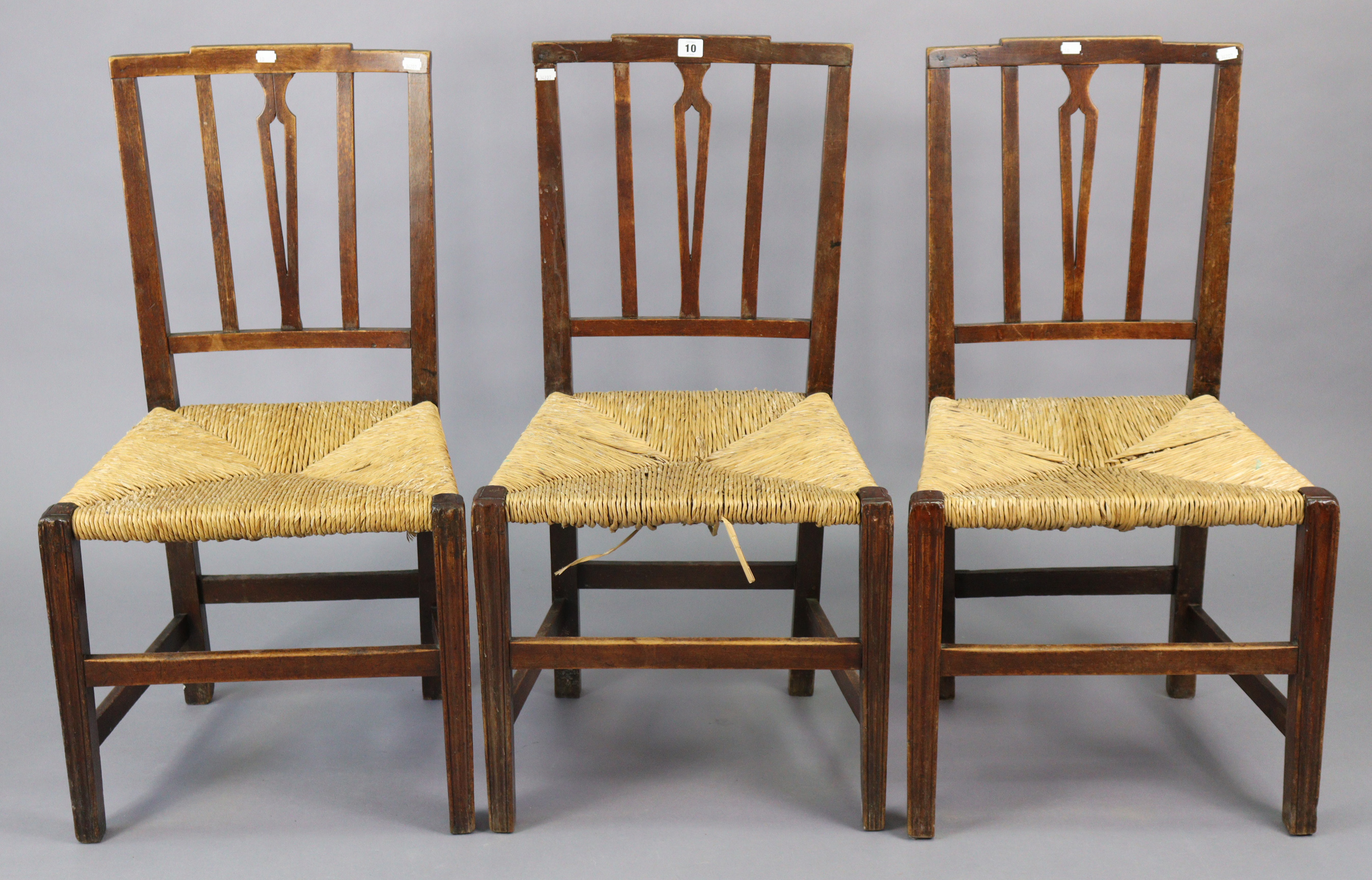 A set of three early 20th century splat-back dining chairs each with a woven-rush seat, & on