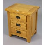 A light oak bedside chest fitted three long drawers, 21½” wide x 25” high.