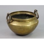 An eastern brass large circular vessel with iron ring side handles, 15½” wide x 11¼” high (opening