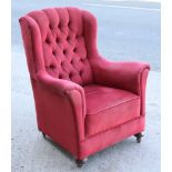 A mid-20th century button-back armchair upholstered crimson velour, & on bun feet with Shepherd