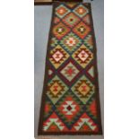 A Maimana kilim runner of dark green ground with repeating lozenge motif, 210cm x 61cm.