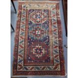 An antique Kazak-style rug with three hook-bordered octagonal panels to the dark blue centre