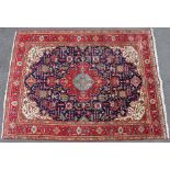 A Persian carpet with crimson & turquoise centre medallion on a dark blue ground, all-over