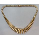 A 9ct. gold flexible necklace with fringe of baton links to the front; 41`cm long. (22 gm).