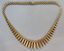 A 9ct. gold flexible necklace with fringe of baton links to the front; 41`cm long. (22 gm).