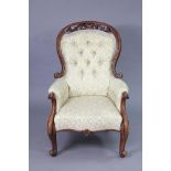 A Victorian mahogany frame armchair with padded seat & arms & buttoned back, on carved cabriole