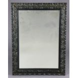 A rectangular bevelled wall mirror in foliate carved & ebonised wooden frame, 74cm x 54cm.