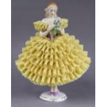 A Sitzendorf porcelain standing female figure in yellow lace dress, on gilt decorated circular base,