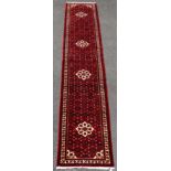A Persian Hosseinabad corridor runner of madder ground with all-over multicoloured close floral