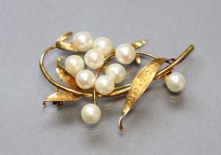 A 14K foliate brooch set ten cultured pearls, 4.8 cm long. (6.4 gm).