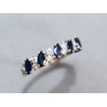 A 9ct. gold ring set row of five oval-cut sapphires with pairs of small white stones in between;