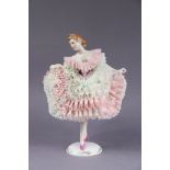 A Sitzendorf porcelain figure of a female dancer in pink & white lace dress, on gilt decorated