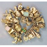 A 9ct. gold curb-link bracelet with padlock clasp, & thirty four various pendant charms, all with