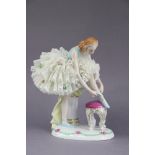 A Sitzendorf porcelain figure of a ballerina tying her shoe, on oval base with floral border, 18.5cm