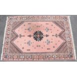 A Moroccan carpet of pink ground with central stylised floral motif & scattered flowers within