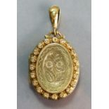 A late Victorian yellow metal oval pendant photo. locket, the engraved front with border of seed