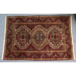 A Kazak rug of ochre ground with row of three lozenges surrounded by repeating geometric designs,