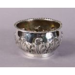 A silver deep bowl of squat round form with crimped rim, the sides with embossed foliage, on plain