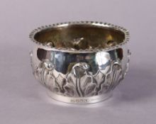 A silver deep bowl of squat round form with crimped rim, the sides with embossed foliage, on plain