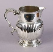 A silver jug with plain cylindrical neck, fluted ovoid body, scroll handle, & on moulded circular