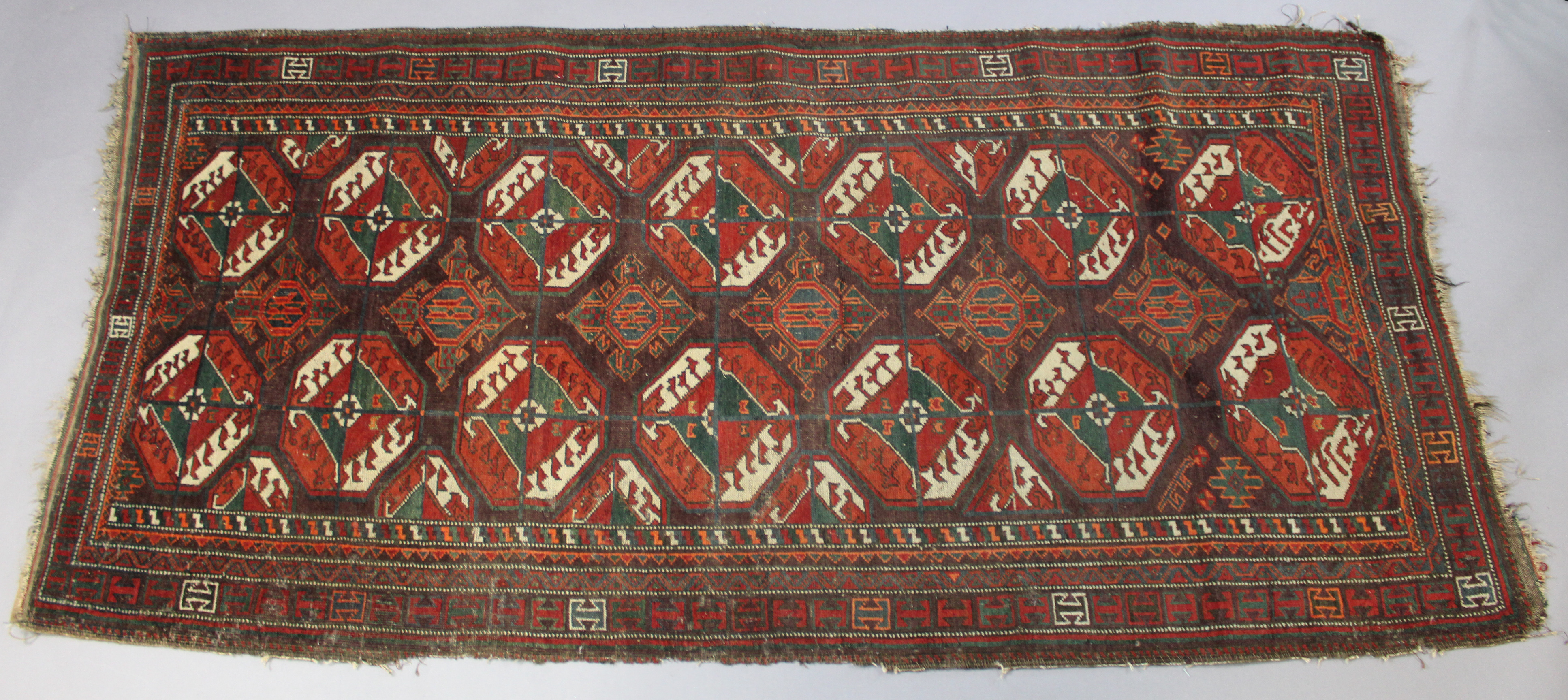 An antique Caucasian rug of multicoloured geometric design with two rows of seven octagonal panels