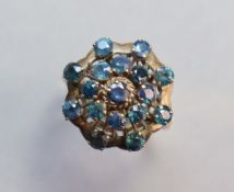 A 14K yellow ring set seventeen small sapphires in tiered concentric rows; size: Q; 4.4. gm.