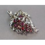 A white metal pendant of foliate design, set eleven oval-cut rubies & numerous small white stones,