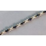 A 9ct. gold flexible bracelet set alternating dark blue & small white sapphires, 18.5 cm long. (8.