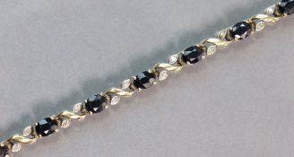 A 9ct. gold flexible bracelet set alternating dark blue & small white sapphires, 18.5 cm long. (8.
