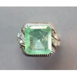 AN EMERALD & DIAMOND RING, the trap-cut emerald of pale colour & weighing approx. 5.4 carats, set