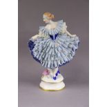 A Sitzendorf porcelain figure of a female dancer in blue lace dress, on circular base with gilt line