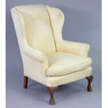 A Victorian mahogany frame wing-back armchair upholstered cream-coloured fabric, with loose seat