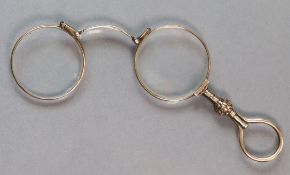 A pair of late 19th century yellow metal lorgnettes with folding round lenses & floral knop to the