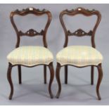 A pair of 19th century simulated rosewood carved balloon-back dining chairs each with a padded seat,