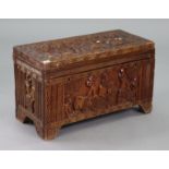 An African carved hardwood trunk with all-over figure-scene decoration, with a hinged lift-lid, & on