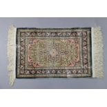 A Turkish Hereke tiny silk rug of ivory & deep blue ground, & with all-over repeating multi-coloured