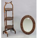 A carved wooden oval wall mirror inset with a bevelled plate, 21” x 15¼”; together with a three-tier