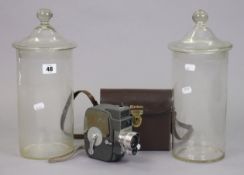 A Keystone “Electric Eye” 8mm cine-camera, with case; & a pair of clear glass cylindrical storage