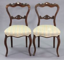 A pair of 19th century simulated rosewood carved balloon-back dining chairs each with a padded seat,