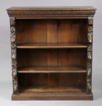 A Victorian carved oak standing open bookcase having three adjustable shelves, & on a plinth base,