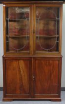 A 19th century mahogany tall cabinet the upper part with two adjustable shelves enclosed by a pair