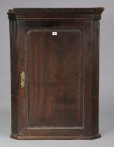 A 19th century mahogany hanging corner cupboard fitted three shaped shelves enclosed by a panel door