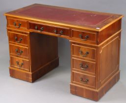 A reproduction yew wood pedestal desk inset gilt-tooled crimson leather, fitted with an
