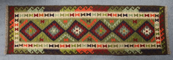 A kilim runner of green ground with multicoloured geometric design, 206cm x 63cm