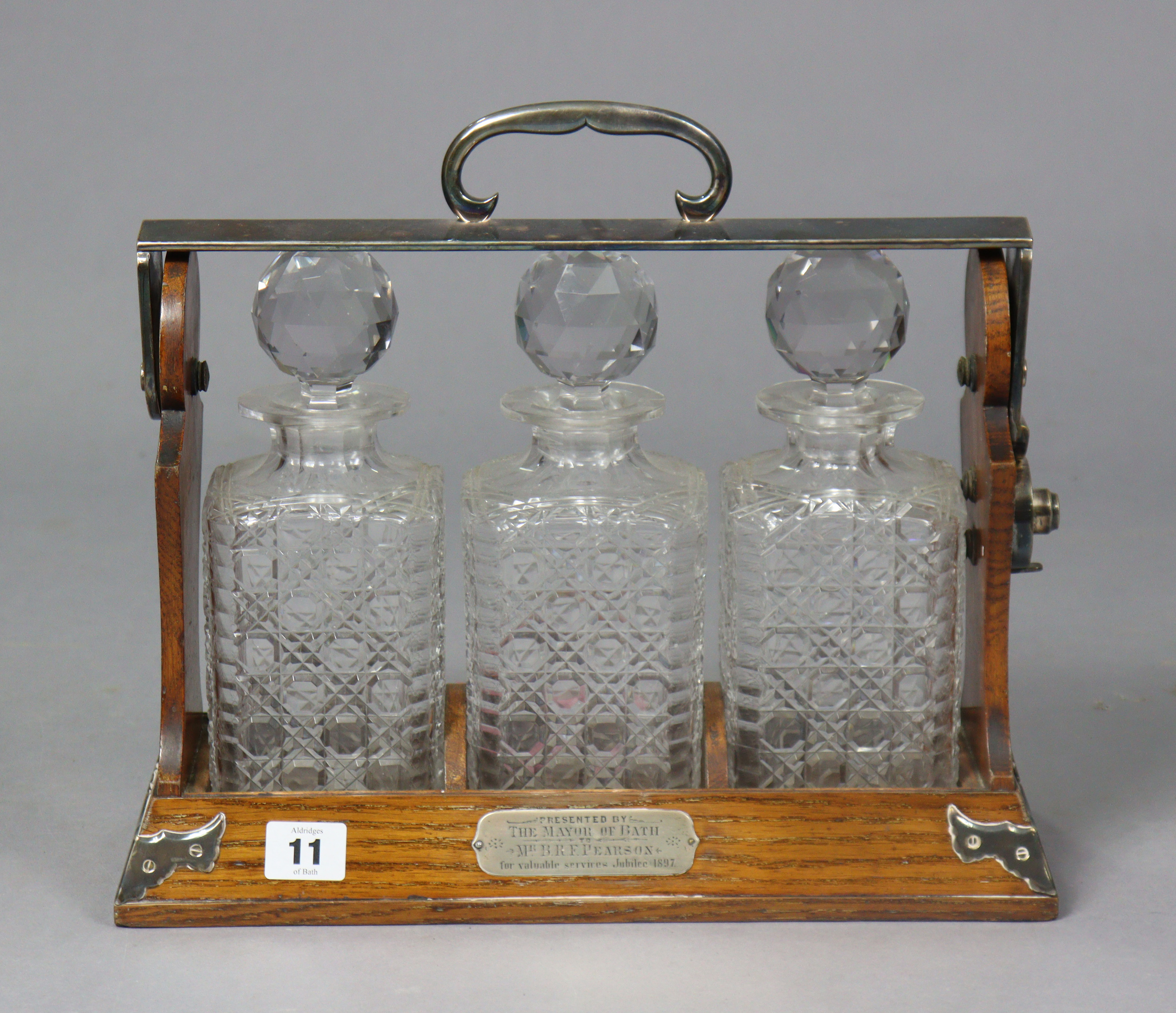 A late 19th century Betjaman’s patent oak tantalus having plated mounts, & fitted three cut-glass