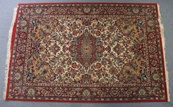 A Persian pattern rug of crimson & ivory ground; & with all-over multi-coloured floral design to