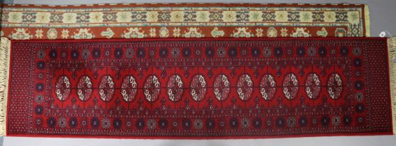 A Persian pattern corridor runner of crimson & ivory ground & with a row of thirteen guhls to centre