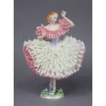 A Sitzendorf porcelain figure of a ballerina wearing white & pink lace dress, on floral-encrusted
